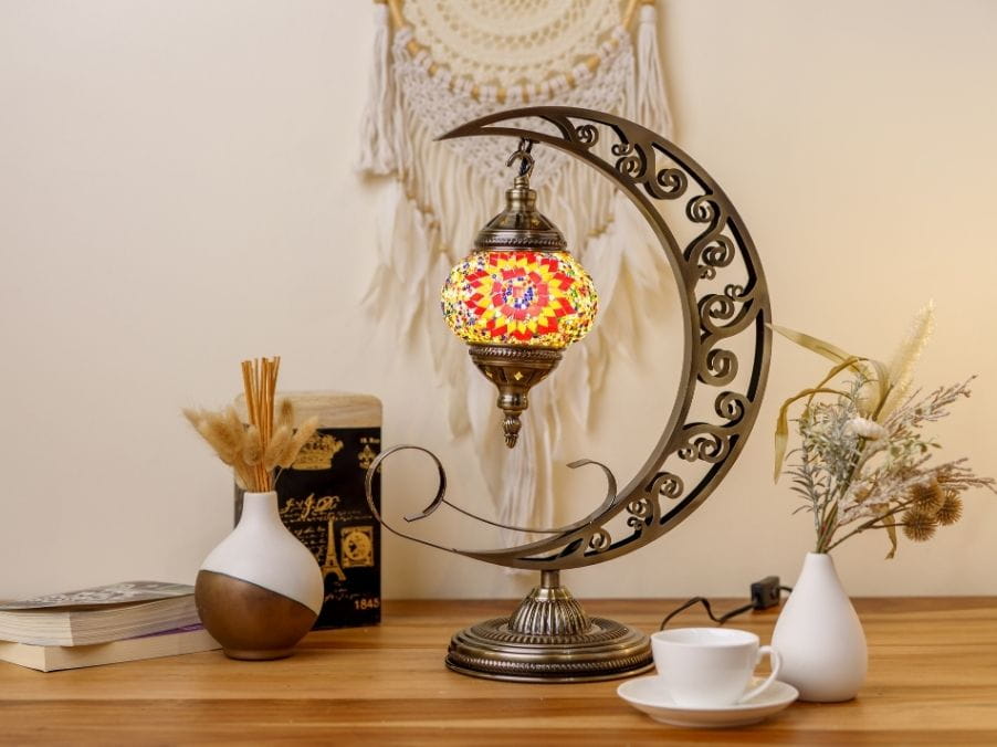 Decorative moon lamp on a wooden surface with books and vases in the background