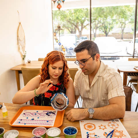 Two people sitting at a table with craft materials, engaged in an activity. Turkish Lamp Workshop
