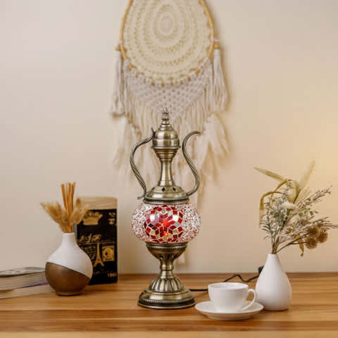 Decorative aladdin lamp with mosaic design on a wooden surface, surrounded by books and small vases.
