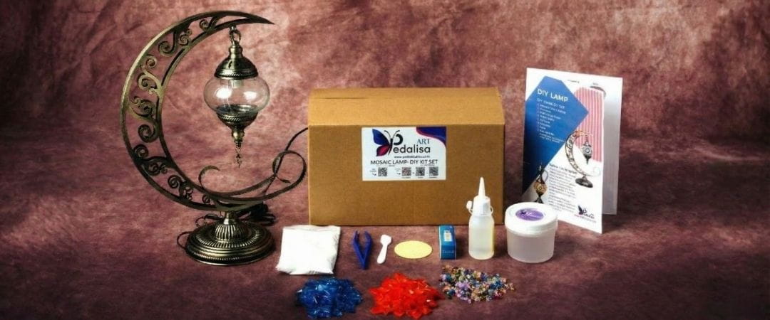 DIY craft kit with a box, lamp, and various items on a brown background