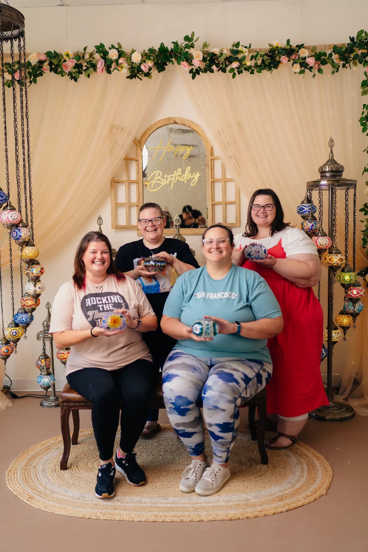 Four people posing together in a decorated room with 'Happy Birthday' sign