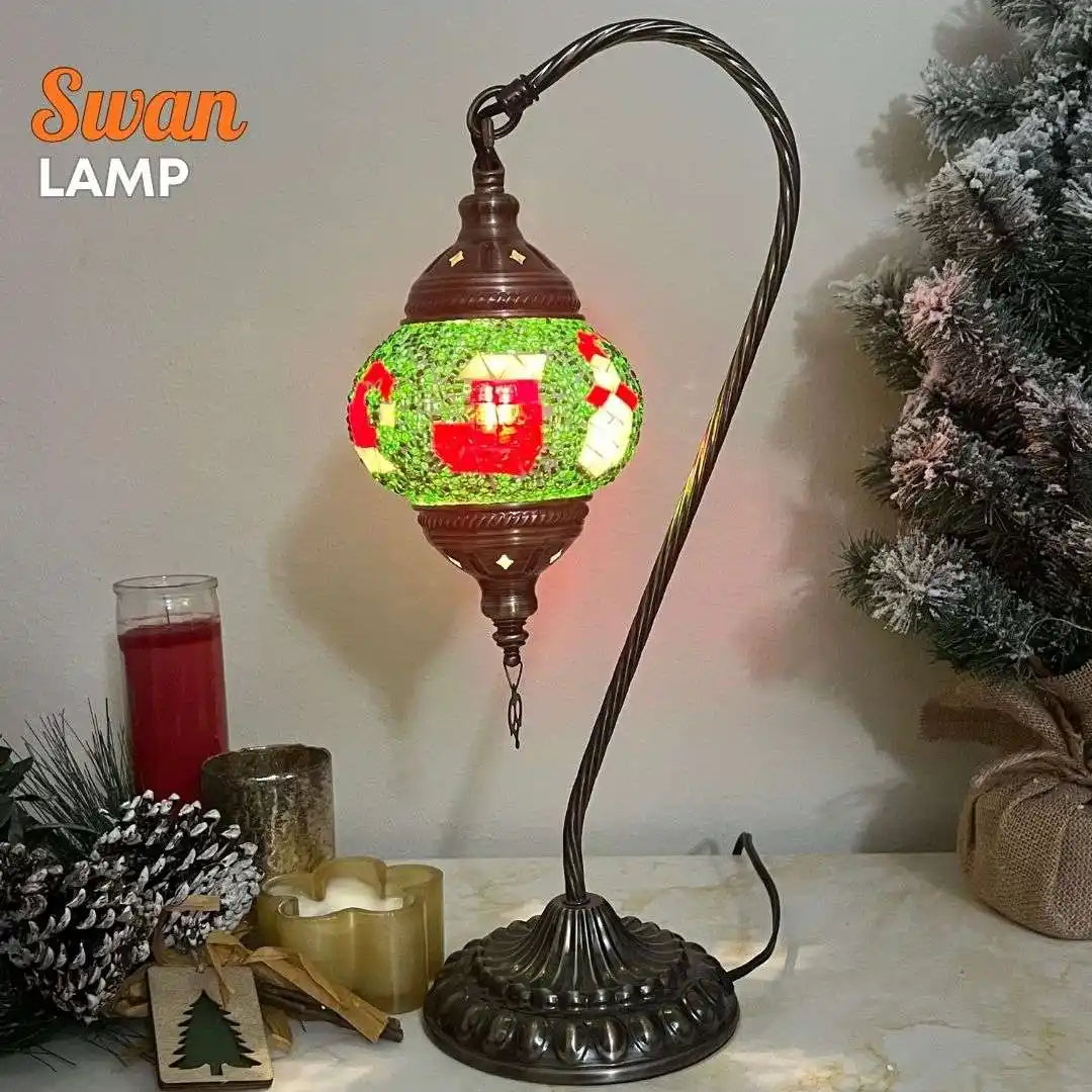 Decorative lamp with a festive design on a table with candles and a Christmas tree.
