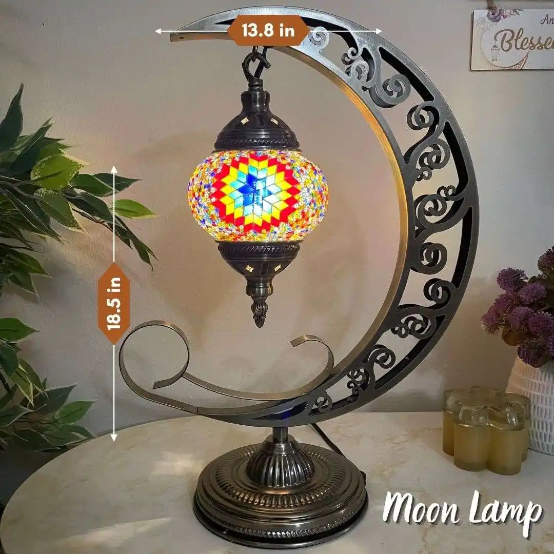 Decorative moon-shaped lamp with colorful glass shade on a table.