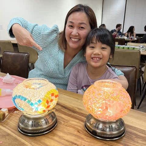 Woman and child sitting at a table with decorative lamps in a restaurant setting