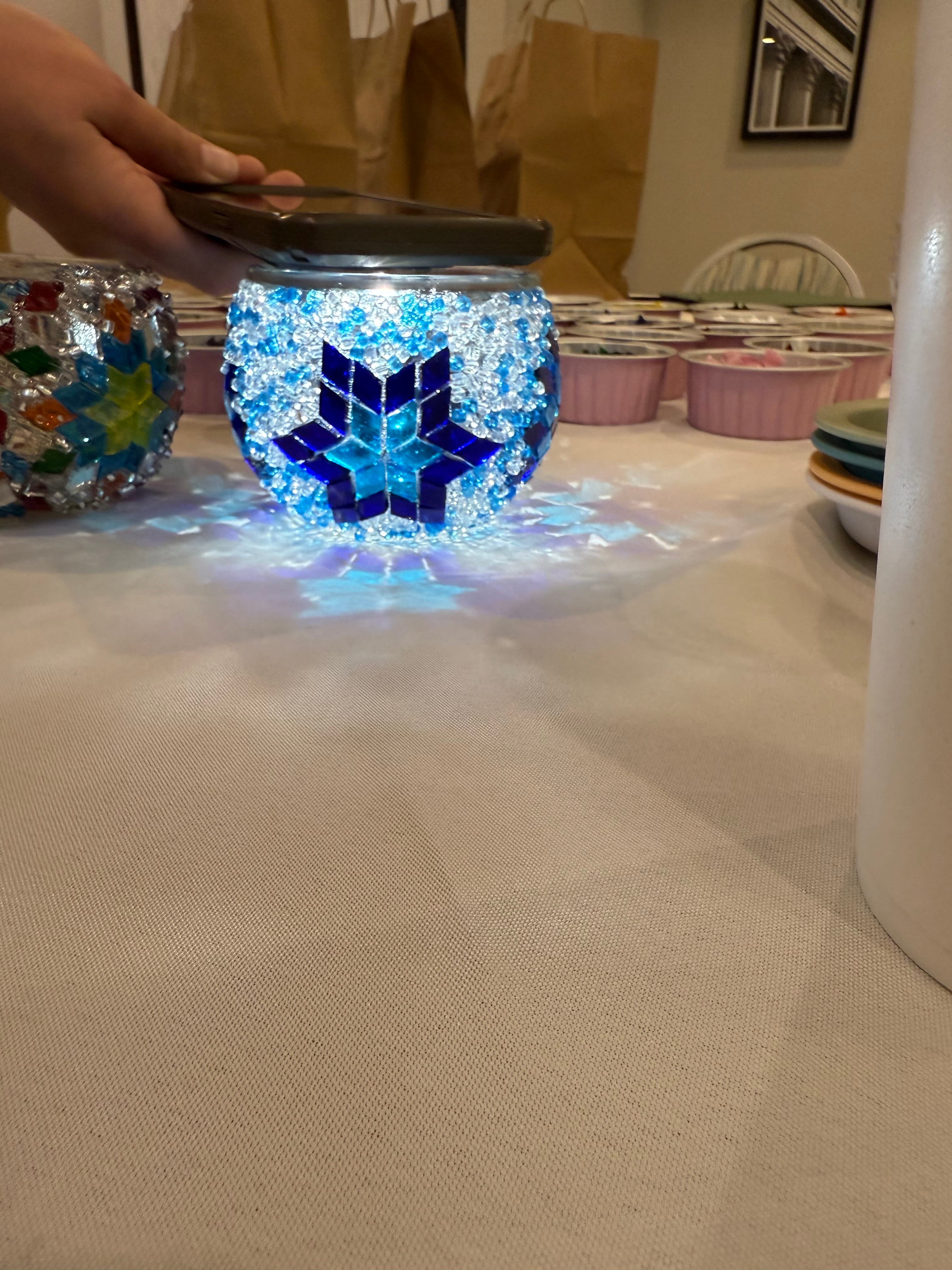 Decorative glass jar with blue and white design on a textured surface