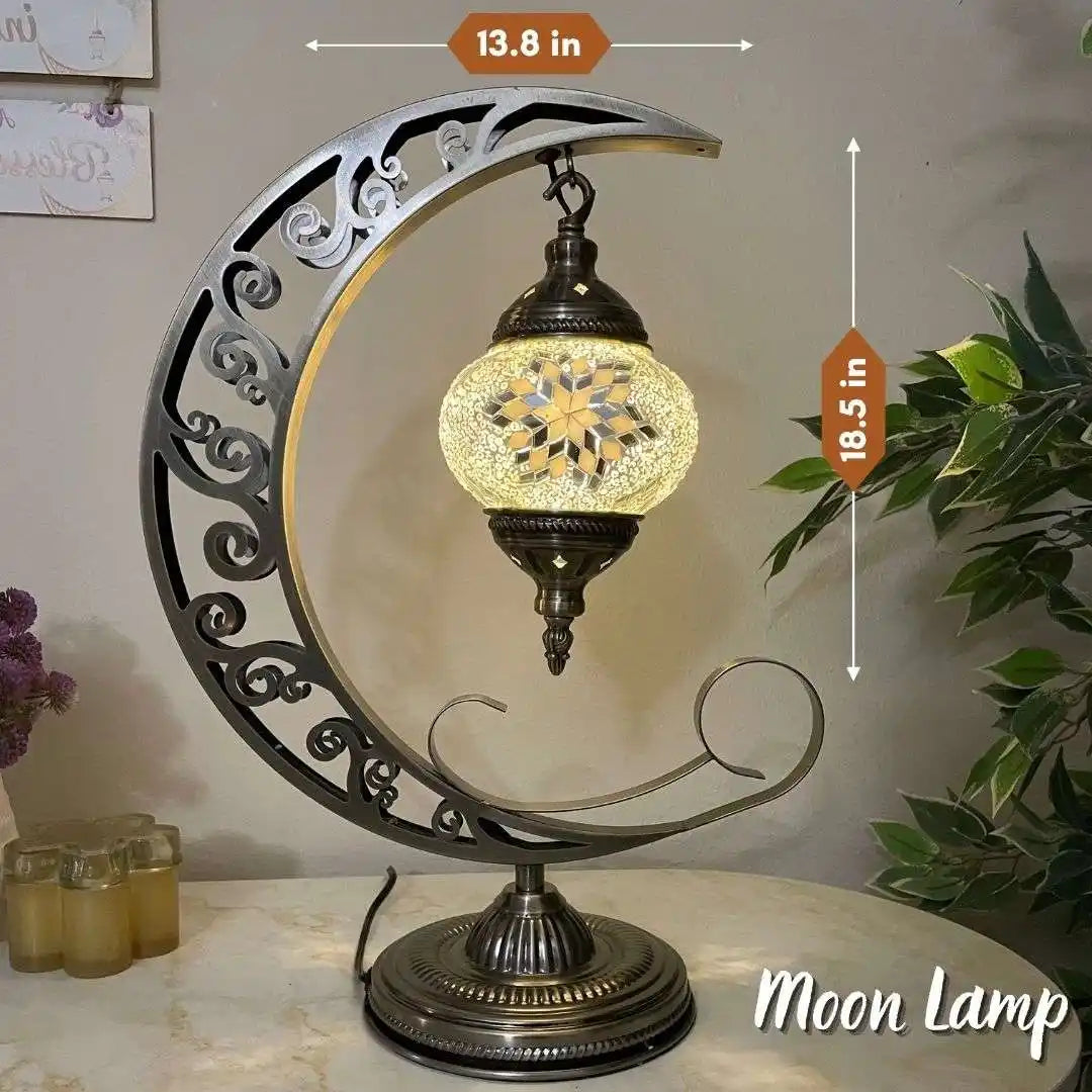 Decorative Turkish Moroccan mosaic moon lamp with intricate design and glowing light, placed on a surface with plants and candles in the background.