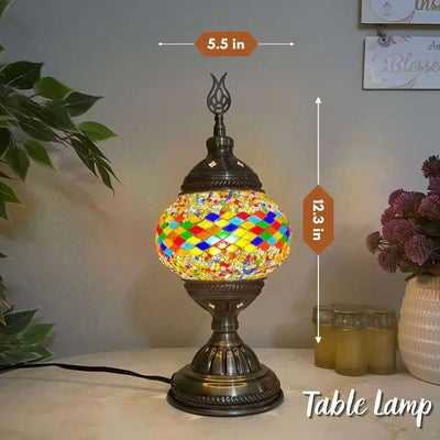 Turkish Moroccan mosaic Table lamp with colorful mosaic design, dimensions indicated, on a surface with plants and jars in the background.