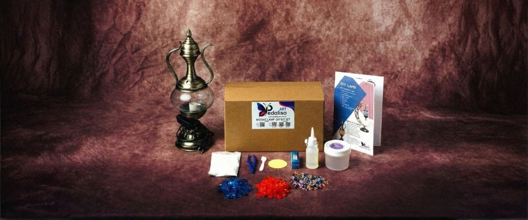 DIY Kit of craft supplies including a box, lantern, and mosaic materials on a textured brown background
