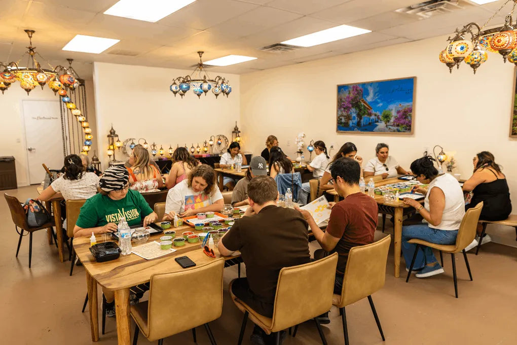 Group of people sitting around tables in a room with artwork on the walls.