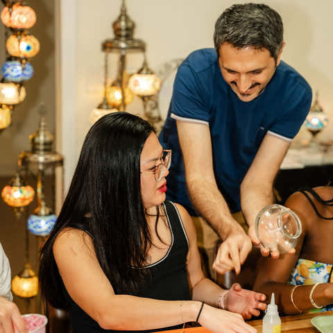 Two people interacting at a table with decorative hanging lights in the background