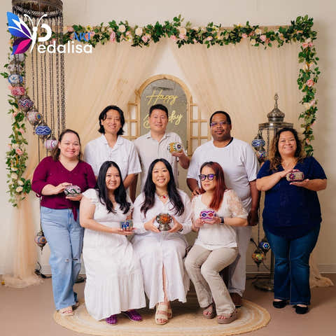 Group of people posing for a photo in front of a decorated backdrop with 'Pedalisa Art' branding. Group Event