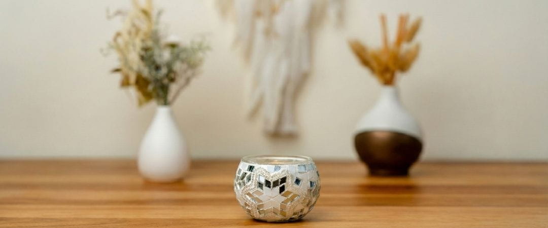 Decorative candle holder on a wooden surface with two vases in the background.